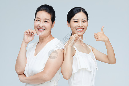 中年女性和年轻美女一起拿牙套展示图片