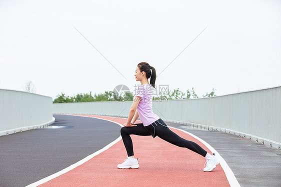 青年女性户外热身压腿图片