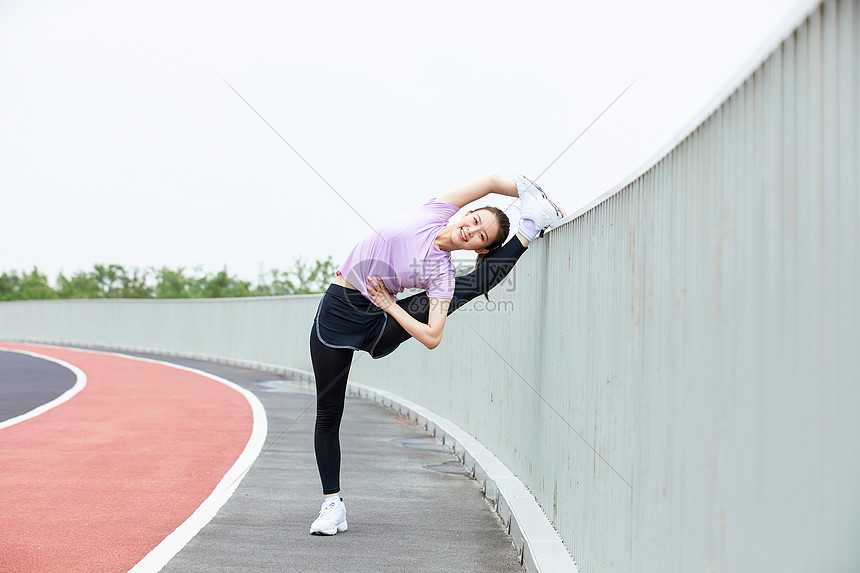 青年女性户外热身压腿图片