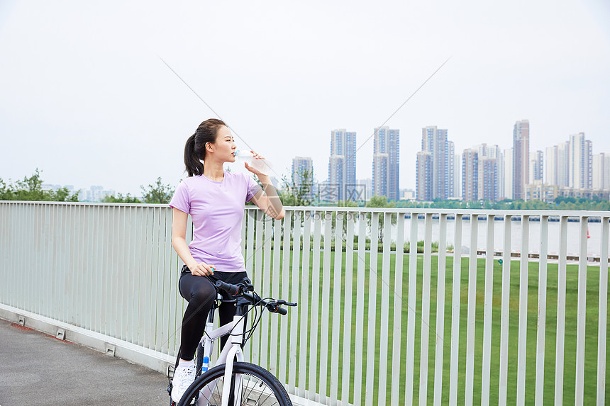 青年女性户外公园骑行休息喝水图片