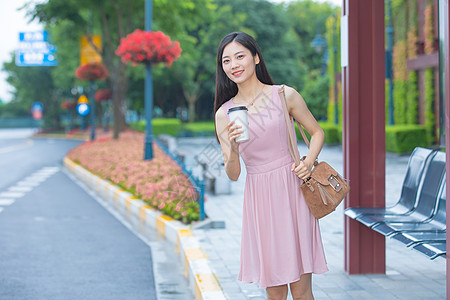 等待公交车的青年女性手捧咖啡杯背景