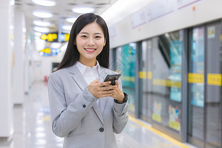 上班路上的人商务女性在地铁站玩手机背景