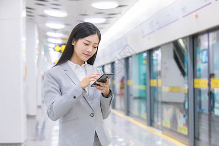 上班通勤女性白领在地铁旁刷手机背景