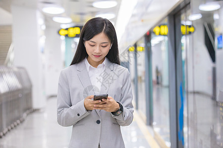商务女性在地铁站玩手机高清图片