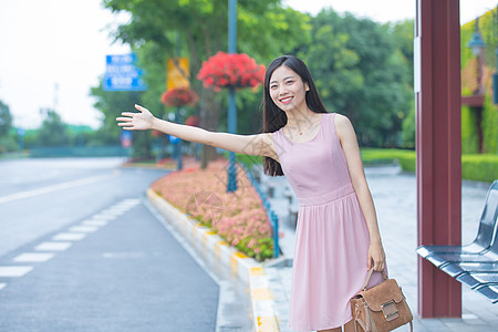 在公交车站台挥手打车的青年女性图片