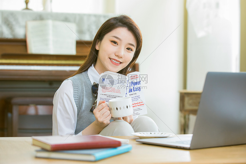 在客厅内喝咖啡学习的女大学生图片