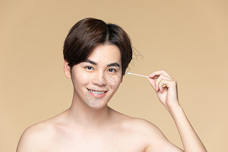 青年男性用棉签清洁耳朵背景图片