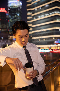 夜晚都市天桥上的商务男性手捧咖啡图片