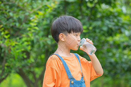 树林前男孩拿着水杯喝水图片