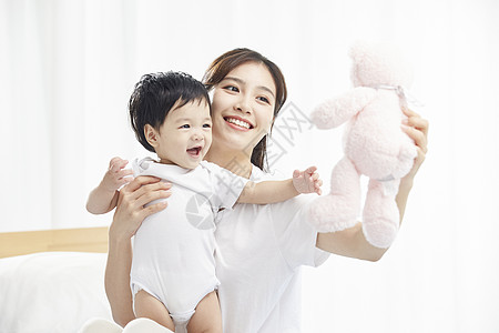 中国妈妈孩子年轻妈妈用毛绒玩具逗宝宝开心背景