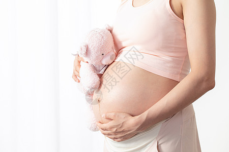 孕妇抱着毛绒玩偶背景图片