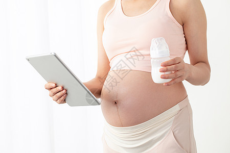 孕妇拿着平板电脑和奶瓶图片