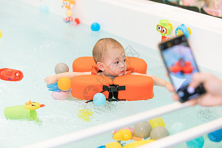 手机拍摄带着游泳圈游泳的婴儿图片