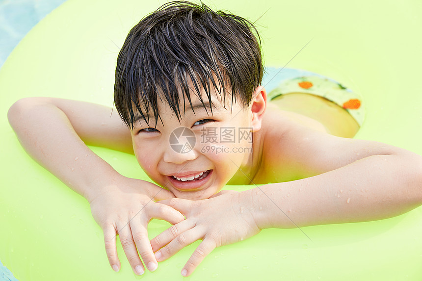 小男孩泳池里趴在游泳圈上
