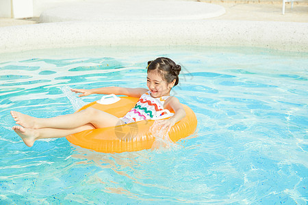泳装小女孩躺在泳池里的游泳圈上背景