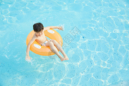 小男孩躺在泳池里的游泳圈上图片