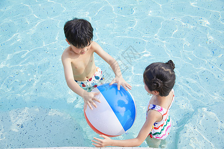 小男孩和小女孩在泳池玩球图片