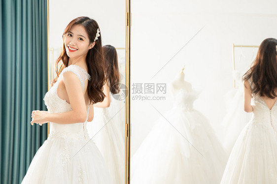 在镜子前试穿婚纱的甜美新娘图片