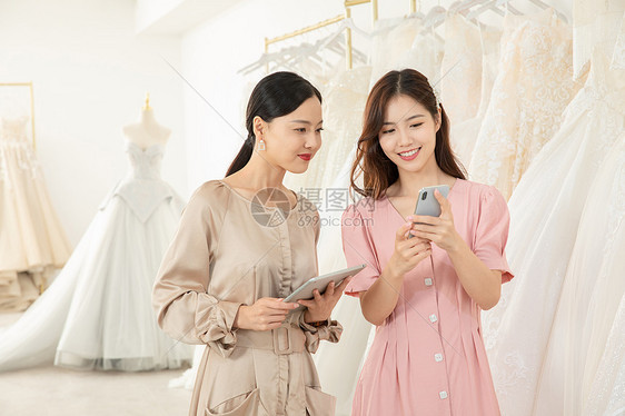 服务员使用平板电脑为顾客介绍婚纱图片