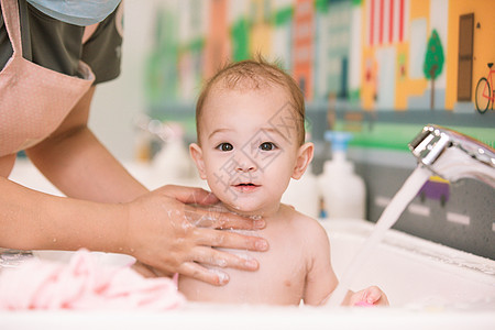 阿姨给婴幼儿洗澡特写背景图片