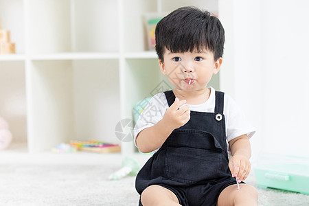 婴儿坐可爱幼儿宝宝坐地毯上吃糖果背景