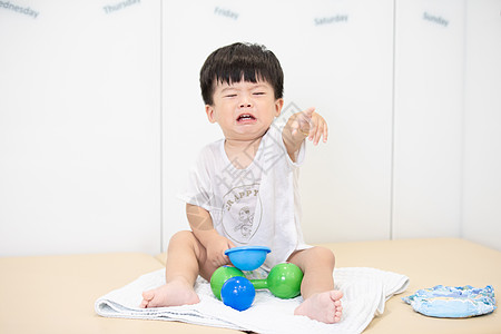 小孩子喝奶可爱宝宝坐在毯子上哭闹背景