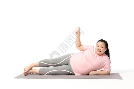 肥胖女生躺在瑜伽垫手指上方图片