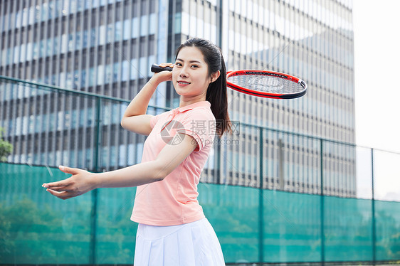 网球挥拍姿势的年轻粉色衣服美女图片