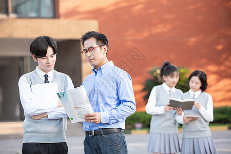 校园里学生和老师讨论课本知识图片