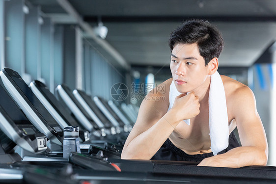 在跑步机上休息的肌肉男性图片