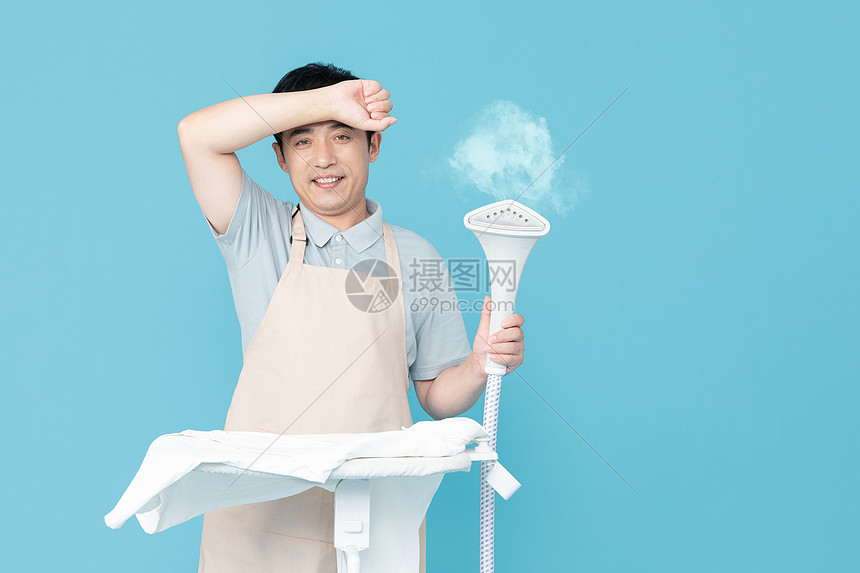 手持挂烫机的家政服务男性擦汗图片