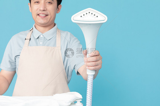 使用挂烫机熨烫衣服的家政服务男性特写图片