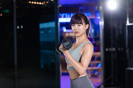 运动女性年轻女士健身房哑铃训练背景