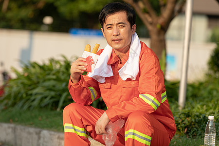 坐在马路旁吃油条的环卫工人图片