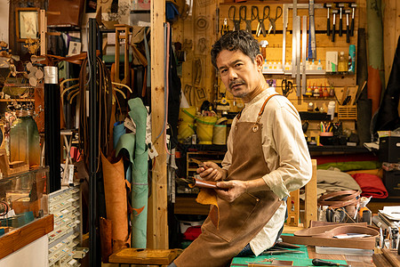 中年男性皮匠工匠坐工作台上图片