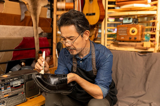 中年男性鞋匠工匠给皮鞋刷鞋油图片