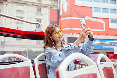在观光大巴上用手机自拍的女青年图片