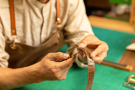 中年男性皮匠手工缝制皮带细节高清图片