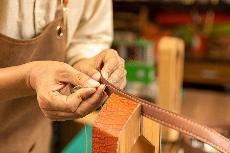 皮料中年男性皮匠手工缝制皮带细节背景