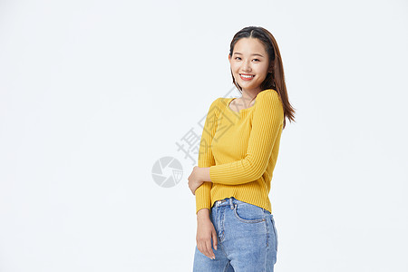 穿牛仔裤的美女穿黄色毛衣自信微笑的长发美女背景