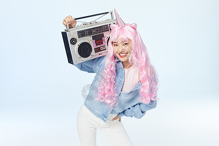 录音机放在肩膀上单手叉腰的时尚粉色长发美女高清图片