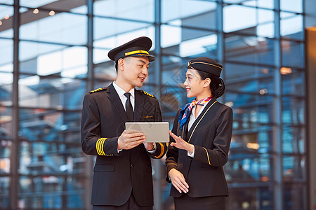 制服空姐飞行员和空姐手持平板交谈背景