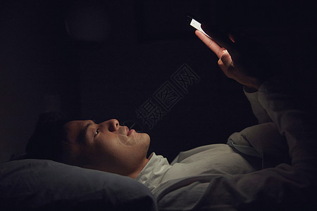 男士发型年轻男士深夜躺在床上玩手机背景