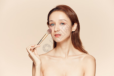 女性拿粉笔刷化妆背景图片