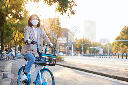 佩戴口罩与手套的都市女性骑共享单车图片