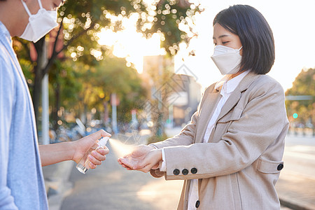 户外使用酒精喷雾消毒除菌的青年情侣高清图片