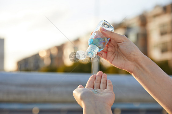 户外使用免洗洗手液除菌的女性特写图片