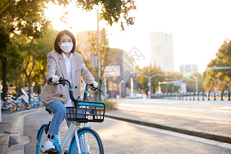 佩戴口罩与手套的都市女性骑共享单车图片