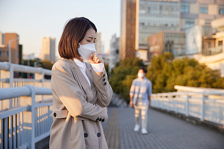 户外佩戴口罩咳嗽的青年女性图片