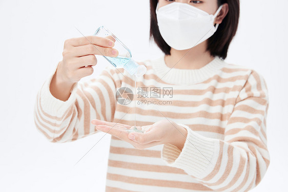 佩戴口罩的女性使用免洗洗手液图片